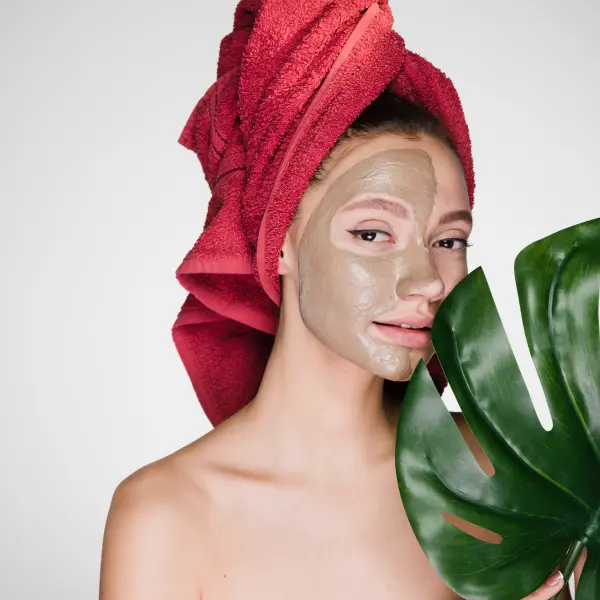woman with facial creme holding large leaf